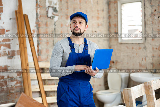 Builder handyman checking plan of house renovation on laptop. Стоковое фото, фотограф Яков Филимонов / Фотобанк Лори