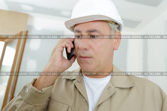 builder on the phone by a ladder. Стоковое фото, агентство Ingram Publishing / Фотобанк Лори