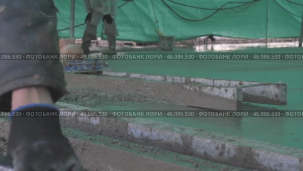 Builders leveling the concrete base строители выравнивают бетонную подложку. Стоковое видео, видеограф Опока Алексей / Фотобанк Лори