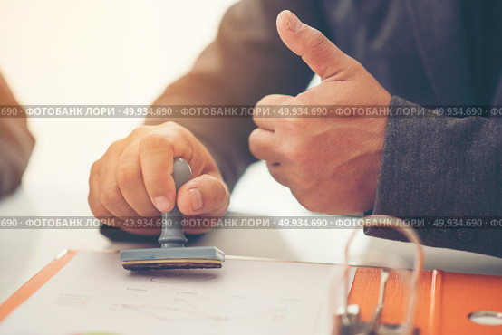 Business hand putting stamp on a document, close up. Стоковое фото, агентство Ingram Publishing / Фотобанк Лори