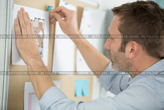 businessman pinning sticky paper memo note on cork board. Стоковое фото, агентство Ingram Publishing / Фотобанк Лори