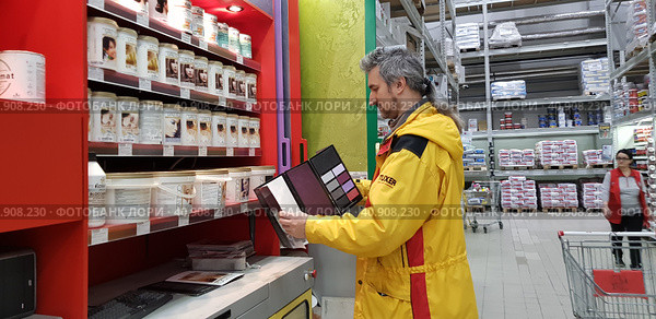 Buyer selects paint and plaster in the store (2018 год). Редакционное фото, фотограф Анна Кривицкая / Фотобанк Лори