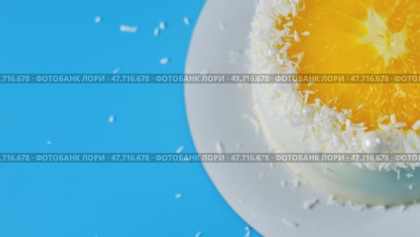 Cake with orange and coconut shavings spinning on a blue background. Стоковое видео, видеограф Mikhail Davidovich / Фотобанк Лори