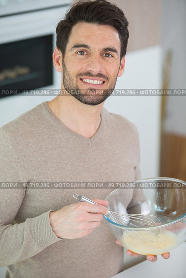 calm adult person standing whisking eggs in the bowl. Стоковое фото, агентство Ingram Publishing / Фотобанк Лори