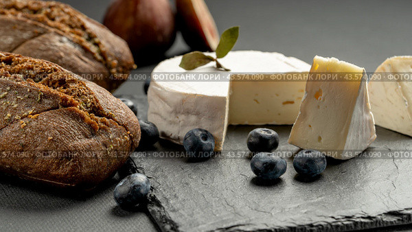 Camembert cheese with figs and blackberries and blueberries on a black wooden table. Wine food and romantic, cheese and bread delicacies. Стоковое фото, фотограф Igor Skripachev / Фотобанк Лори