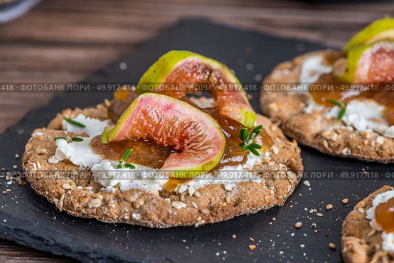 Canape or crostini with multigrain  crispread with cream cheese and fig jam on a slate board. Delicious appetizer ideal as an aperitif. Стоковое фото, агентство Ingram Publishing / Фотобанк Лори