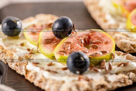 Canape or crostini with multigrain  crispread with cream cheese and fresh fig slices on a wooden board. Delicious appetizer ideal as an aperitif. Стоковое фото, агентство Ingram Publishing / Фотобанк Лори