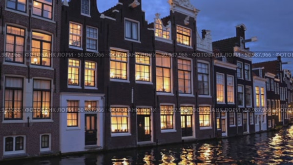 Candlelight glowing from windows casting soft reflections on tranquil waters, illuminating historic Amsterdam canal houses during twilight evening. Стоковое AI-видео, аниматор Данил Руденко / Фотобанк Лори