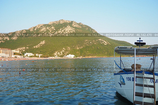Canj, Montenegro 07.20.2024 Boats and a shore with vacationers, sunbathers and swimmers. Hotels, sun umbrellas, Adriatic waves, buoys. Beach tourism. Vacation travel. Summer day. Pebble rock beach. Редакционное фото, фотограф Юлия Петровская / Фотобанк Лори
