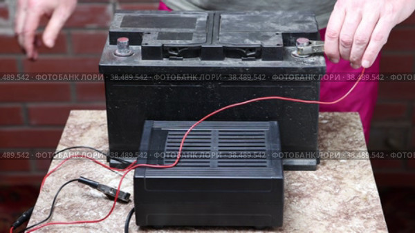 Car battery charger is used at home, motorist attaches alligator clips to contacts. Стоковое видео, видеограф Владимир Григорьев / Фотобанк Лори