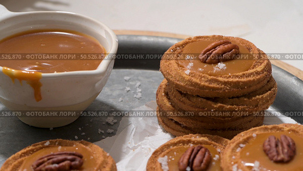 Caramel cookies with pecan nuts served on roud plates, in the kitchen after baking. Стоковое фото, агентство Ingram Publishing / Фотобанк Лори