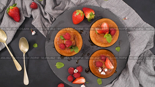Caramel custard puddings on round slate on and dark kitchen countertop. Стоковое фото, агентство Ingram Publishing / Фотобанк Лори