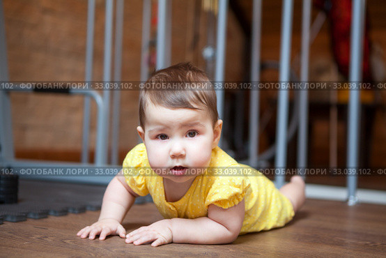 Caucasian baby in yellow bodysuit lying on floor and looking at camera. Стоковое фото, фотограф Кекяляйнен Андрей / Фотобанк Лори