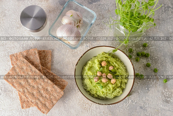 Чаша с вкусным хумусом из зеленого горошка, чесноком и крекерами на светлом фоне. Стоковое фото, фотограф Pixel_shot / Фотобанк Лори