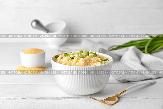 Чаша с вкусным кус-кусом и зеленым луком на светлом деревянном фоне. Стоковое фото, фотограф Pixel_shot / Фотобанк Лори
