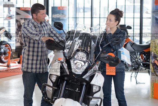 cheerful couple looking at a motorcycle at a salon. Стоковое фото, агентство Ingram Publishing / Фотобанк Лори