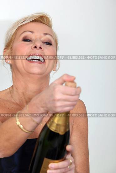 Cheerful woman opening bottle of champagne. Стоковое фото, агентство Ingram Publishing / Фотобанк Лори