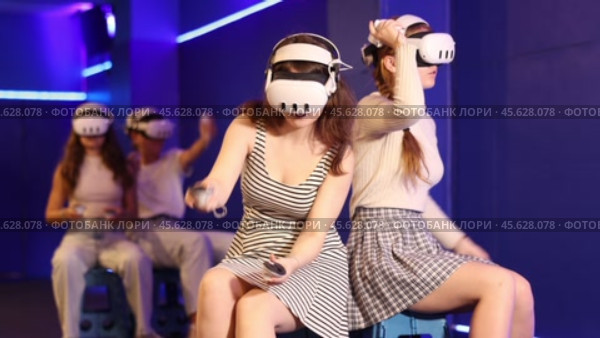 Cheerful young female friends wearing VR headsets and holding controllers having fun in virtual reality studio, competing in two-on-two shooter game. Стоковое видео, видеограф Яков Филимонов / Фотобанк Лори