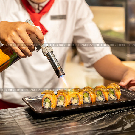 Chef cooking Salmon Foie gras roll, Fusion Japanese Cuisine food, using gas burner torch. Стоковое фото, агентство Ingram Publishing / Фотобанк Лори
