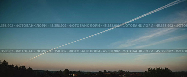 Chemtrail conspiracy theory. Long-lasting condensation trails left in sky by high-flying aircraft are actually chemtrails consisting of chemical or biological agents, sprayed for nefarious purposes. Стоковое AI-изображение, AI-художник Юлия Петровская / Фотобанк Лори
