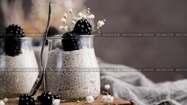 Chia pudding with blackberries, three portions in glass jars on a dark table. Стоковое фото, агентство Ingram Publishing / Фотобанк Лори