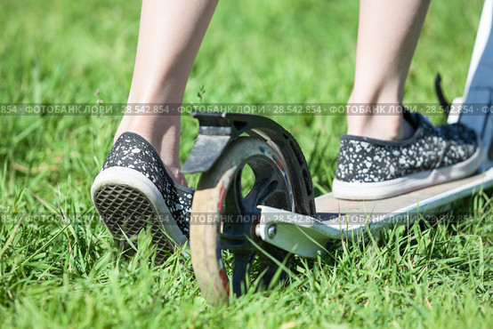 Child drives push stand-up scooter on green grass, close up rear view. Стоковое фото, фотограф Кекяляйнен Андрей / Фотобанк Лори