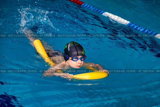 Child Practicing Swimming Indoors With a Flotation Device in an Aquatic Facility. Стоковое фото, фотограф Aleksandr Golubev / Фотобанк Лори
