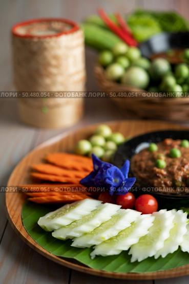Chili paste paste in a bowl with eggplant, carrots, chili, cucumbers in a basket on wood table. Стоковое фото, агентство Ingram Publishing / Фотобанк Лори