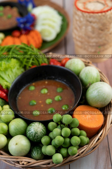 Chili paste paste in a bowl with eggplant, carrots, chili, cucumbers in a basket on wood table. Стоковое фото, агентство Ingram Publishing / Фотобанк Лори