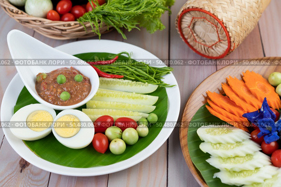 Chili paste paste in a bowl with eggplant, carrots, chili, cucumbers in a basket on wood table. Стоковое фото, агентство Ingram Publishing / Фотобанк Лори