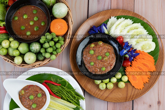 Chili paste paste in a bowl with eggplant, carrots, chili, cucumbers in a basket on wood table. Стоковое фото, агентство Ingram Publishing / Фотобанк Лори