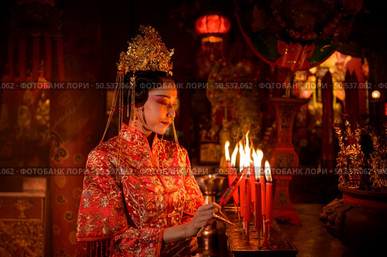 Chinese woman make wishes, pray, and light candles. On the occasion of the annual Chinese New Year festival, in a revered shrine or temple, And in Chinese where candles mean good luck and happiness. Стоковое фото, агентство Ingram Publishing / Фотобанк Лори