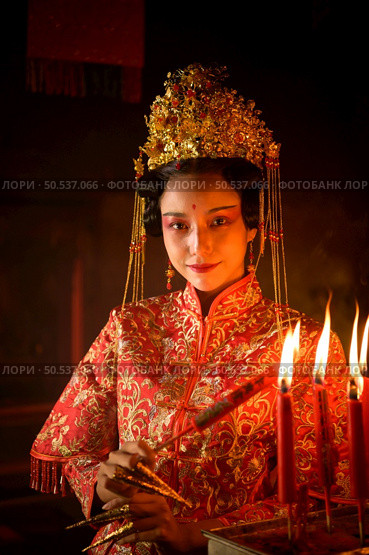 Chinese woman make wishes, pray, and light candles. On the occasion of the annual Chinese New Year festival, in a revered shrine or temple, And in Chinese where candles mean good luck and happiness. Стоковое фото, агентство Ingram Publishing / Фотобанк Лори