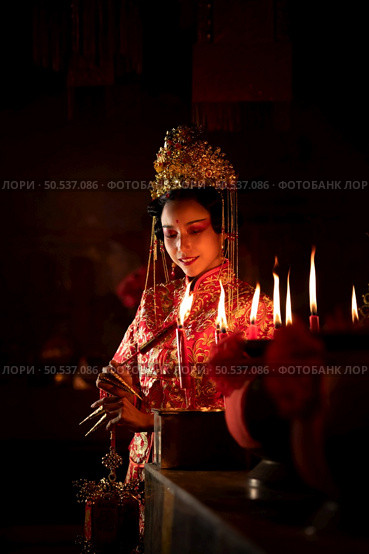 Chinese woman make wishes, pray, and light candles. On the occasion of the annual Chinese New Year festival, in a revered shrine or temple, And in Chinese where candles mean good luck and happiness. Стоковое фото, агентство Ingram Publishing / Фотобанк Лори