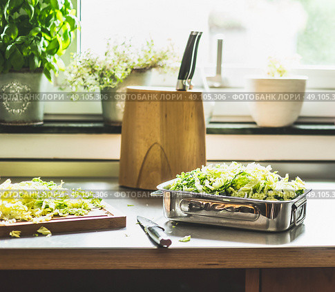 Chopped Savoy cabbage cooking preparation on kitchen table at window. Стоковое фото, агентство Ingram Publishing / Фотобанк Лори