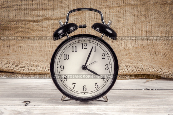 Classic black and white alarm clock on a wooden table. Стоковое фото, агентство Ingram Publishing / Фотобанк Лори