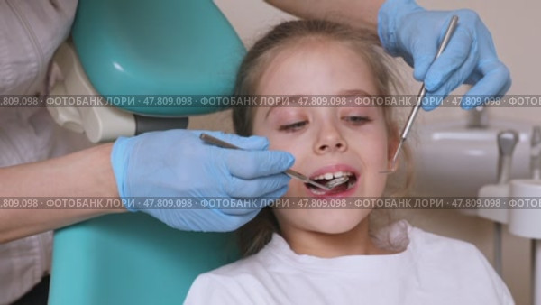 Close up dentist, doctor examines the oral cavity of a little girl, uses a mouth mirror, baby teeth close-up, the concept of pediatric dentistry, dental treatment. Стоковое видео, видеограф Ирина Михайличенко / Фотобанк Лори