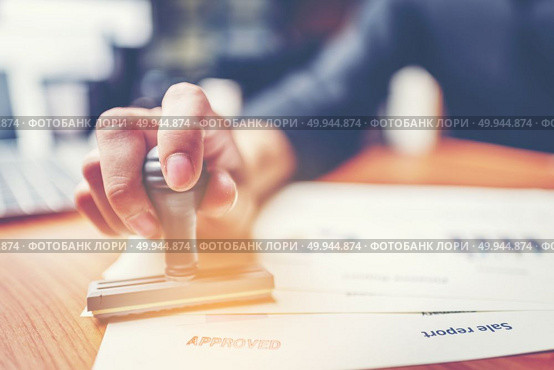 Close-up hand stamping of businessman for signing approval on documents , business concept. Стоковое фото, агентство Ingram Publishing / Фотобанк Лори