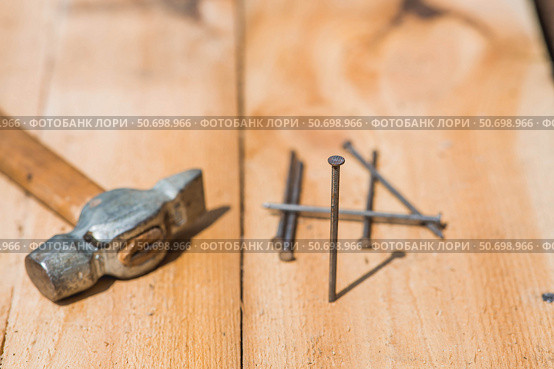 Close-up of a hammer and nails on wooden boards. Hand tools, old construction tools. Стоковое фото, фотограф Photojuli / Фотобанк Лори