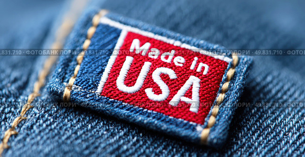 Close-up of a "Made in USA" fabric label stitched on denim, symbolizing American manufacturing, textile quality, and national branding in the fashion industry. Стоковое AI-изображение, AI-художник Катерина Бондарец / Фотобанк Лори