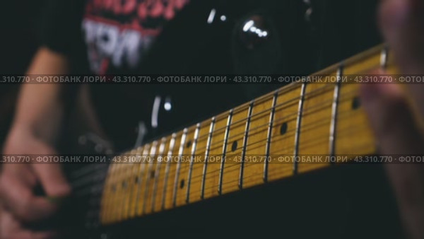 Close-up of a man playing an electric guitar. In the centre of attention is a hand with a plectrum plucking the upper strings. Slow motion of playing the guitar. Стоковое видео, видеограф Воловодов Владимир / Фотобанк Лори