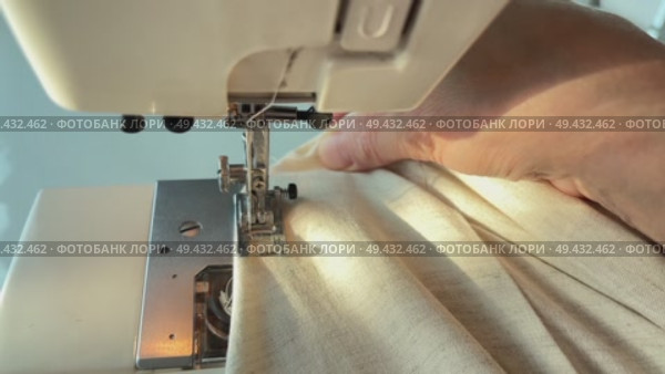 Close-up of a skilled seamstress using a sewing machine to stitch fabric together, demonstrating the complex process of creating clothing and the skill required to sew. Стоковое видео, видеограф Анастасия / Фотобанк Лори