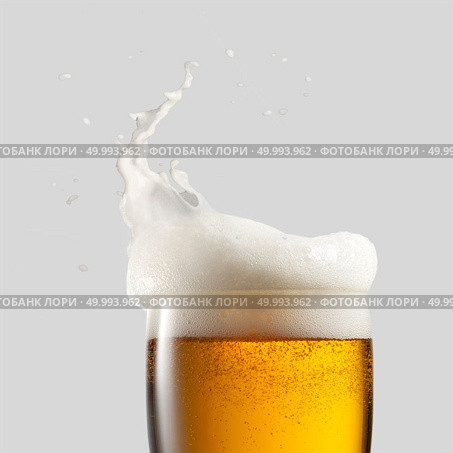 Close-up of cold beer with foam and splash on a gray background. Close-up of cold beer with foam. Стоковое фото, агентство Ingram Publishing / Фотобанк Лори