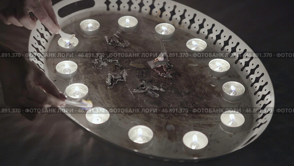 Close up of divinations before Christmas, women hands burning small pieces of paper on the metal tray, traditions and superstitions concept. Стоковое фото, фотограф David Kashakhi / Фотобанк Лори