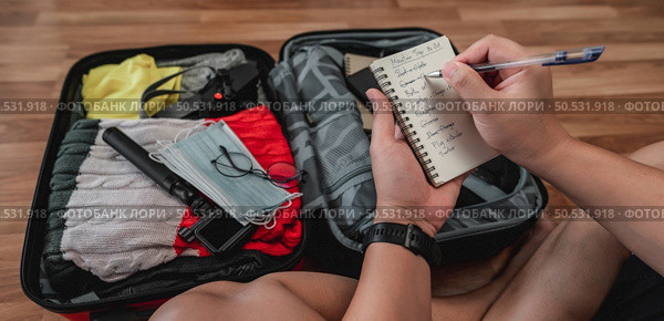 Close-up of man checks the checklist. He’s choosing clothes, travel documents, the itinerary for a solo trip. Travel, holiday and vacation concept. Стоковое фото, агентство Ingram Publishing / Фотобанк Лори
