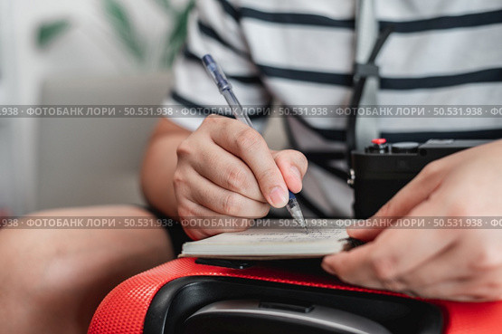 Close-up of man checks the checklist. He’s choosing clothes, travel documents, the itinerary for a solo trip. Travel, holiday and vacation concept. Стоковое фото, агентство Ingram Publishing / Фотобанк Лори