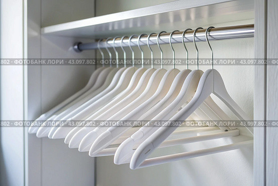 Close-up of white hangers on a white closet. The concept of order and storage in the house. Стоковое AI-изображение, AI-художник Photojuli / Фотобанк Лори