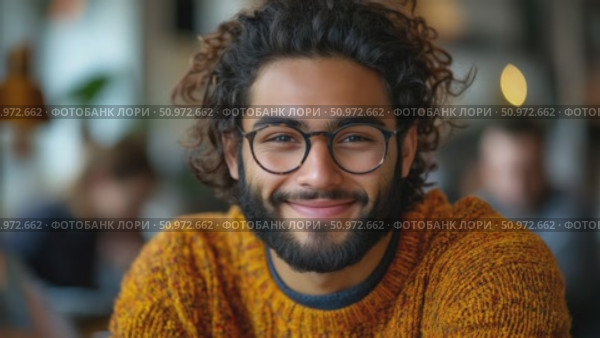Close-up portrait of a young man with curly hair and glasses, smiling warmly in a casual setting. Стоковое AI-видео, аниматор Данила Большаков / Фотобанк Лори