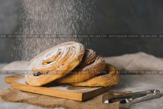 close up sugar dusting baked cinnamon buns chopping board. Стоковое фото, агентство Ingram Publishing / Фотобанк Лори