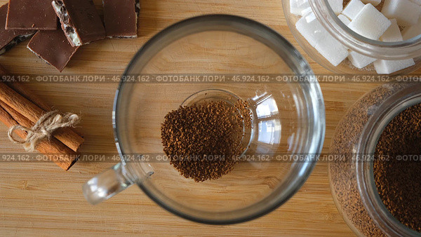 Close up top view of a woman hand putting granulated instant coffee, sugar, and hot water into the mug. Стоковое фото, фотограф David Kashakhi / Фотобанк Лори